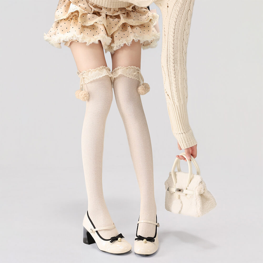 Person wearing beige knee-high socks with lace details and white shoes on a light gray background