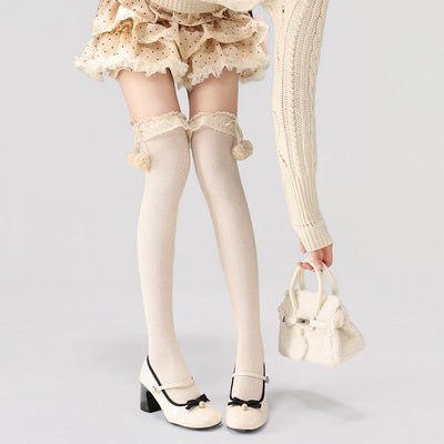 Person wearing beige knee-high socks with lace details and white shoes on a light gray background