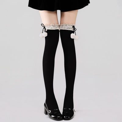 Black tights with lace top and white pom-poms worn by a person on a light gray background