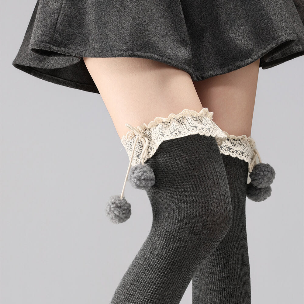 Dark gray tights with lace top and gray pom-poms on a light gray background