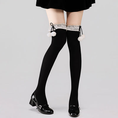 Black tights with lace top and white pom-poms worn by a person on a light gray background