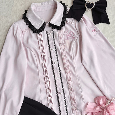 Pink blouse with black lace details and decorative heart bowknow on a light wooden surface