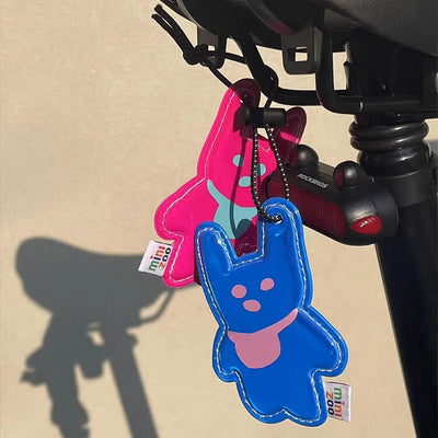 blue and pink reflective rabbit pendants hanging on a bicycle